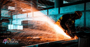 Industrial worker using a grinder with bright sparks flying, symbolizing the skill and energy of Minnesota’s manufacturing industry.